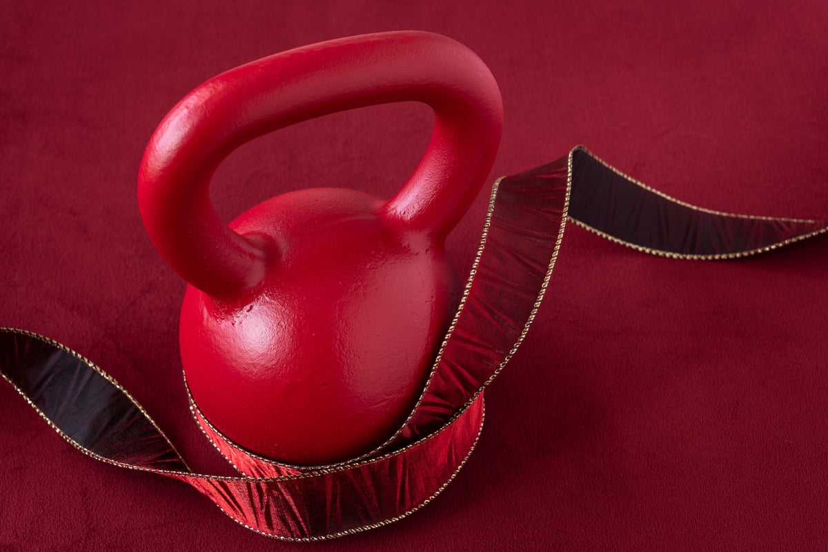 Kettlebell rouge entourée d'un ruban cadeau rouge et or Image