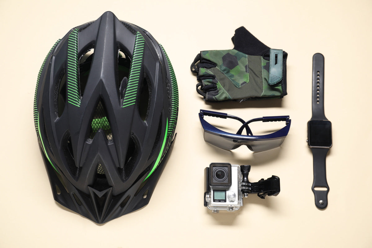 Casque de vélo, gants de cyclisme, lunettes, caméra embarquée et montre connectée posés à plat sur fond beige Image
