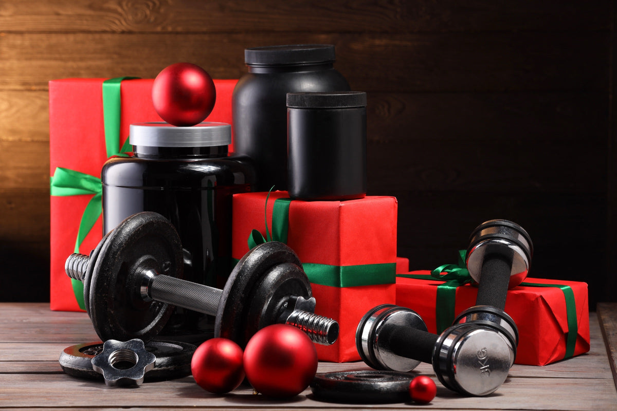 Haltères, pots de compléments alimentaires et paquets cadeaux de Noël sur une table en bois Image