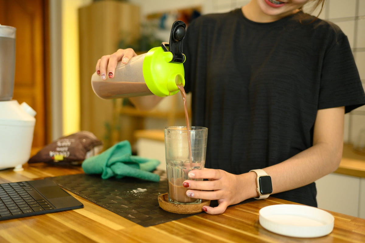 Femme préparant un shake de whey protéine dans sa cuisine Image